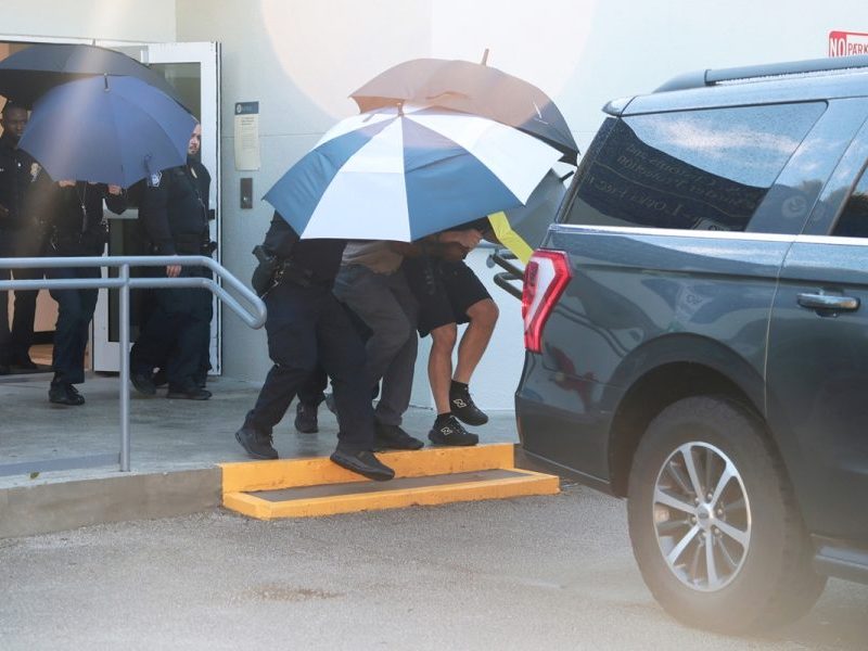 Flávio deixa aeroporto de Miami sob guarda-chuvas para evitar imprensa